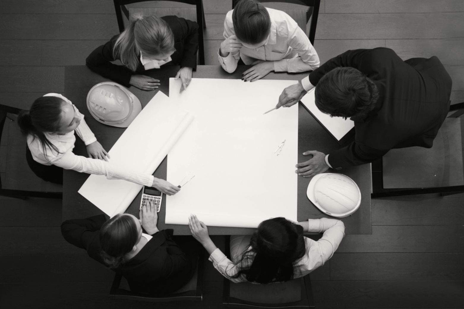 Equipa reunida à volta de uma mesa com desenhos de projeto